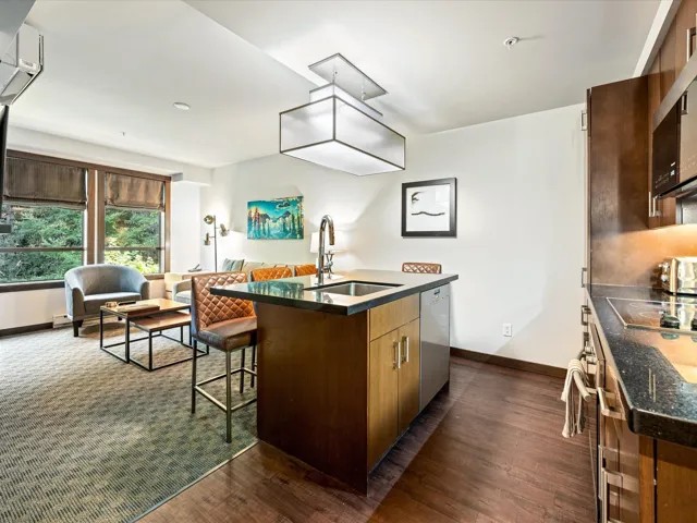 Kitchen with a center island with sink, a kitchen breakfast bar, dark wood-style flooring, open floor plan, and appliances with stainless steel finishes