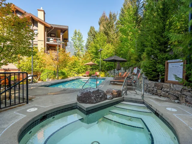 Community pool with a patio, a hot tub, and view of wooded area