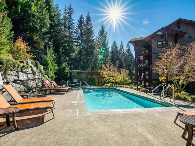 Community pool featuring a patio area and view of wooded area
