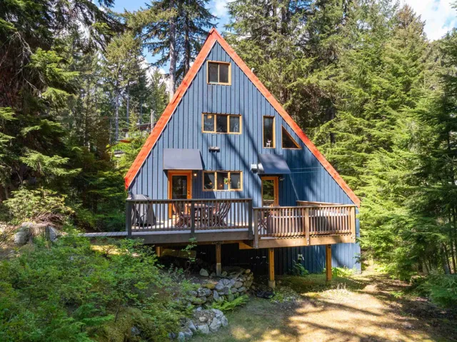 View of front of house with a wooden deck and a wooded view