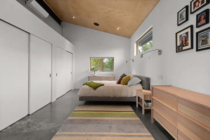 Bedroom featuring vaulted ceiling, finished concrete flooring, and two closets