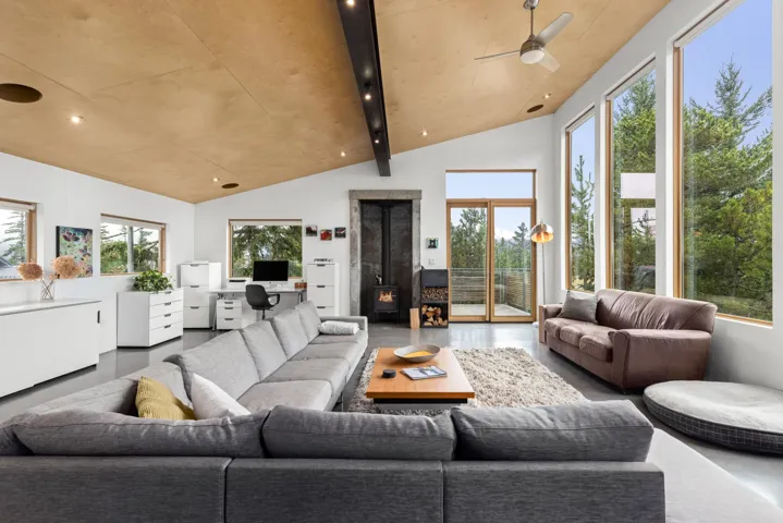 Living room featuring a wood stove, concrete floors, lofted ceiling, an office area, and a ceiling fan