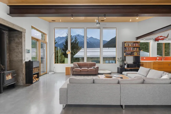 Living area featuring beamed ceiling, a mountain view, a wood stove, finished concrete floors, and healthy amount of natural light