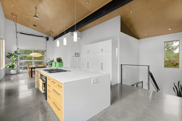 Kitchen featuring decorative light fixtures, concrete flooring, light countertops, modern cabinets, and a kitchen island