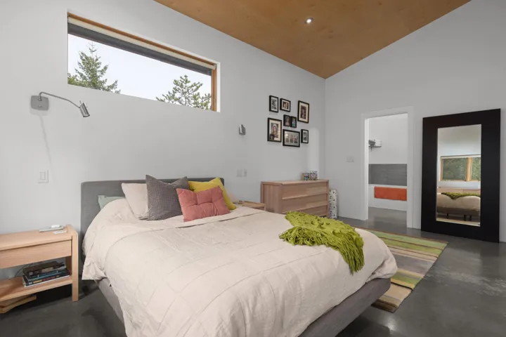 Bedroom with concrete floors, lofted ceiling, multiple windows, connected bathroom, and recessed lighting