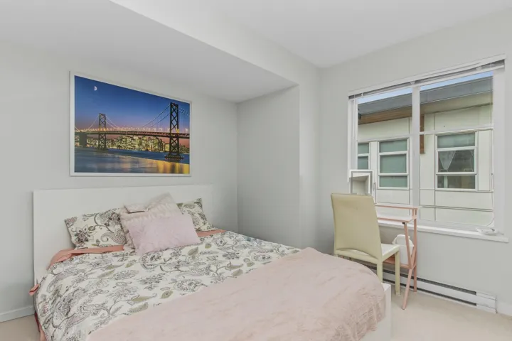 Bright bedroom featuring a large window, neutral wall paint, and light-colored carpeting
