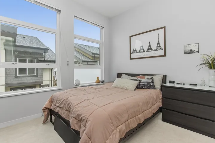 Bright room featuring two large windows with white frames, light-toned carpeting, and light gray walls