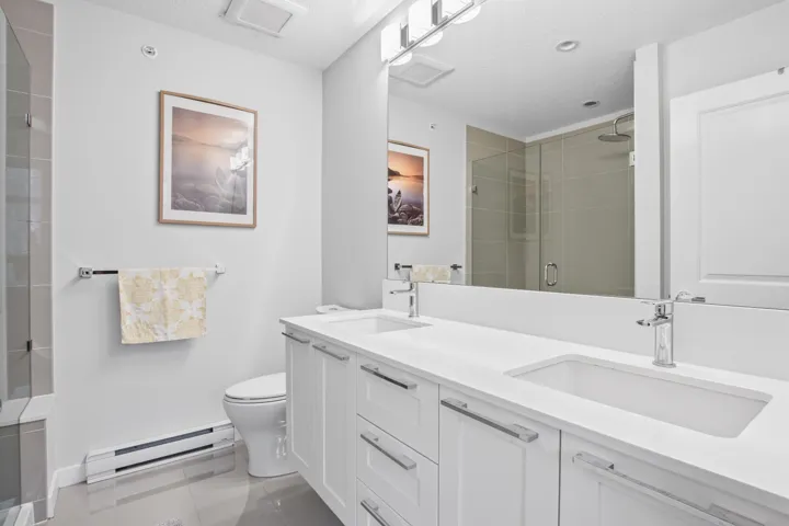 Bathroom featuring a double vanity with white cabinetry, integrated sinks, and chrome faucets