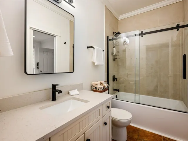 Full bath with vanity, ornamental molding, toilet, shower / bath combination with glass door, and tile patterned flooring