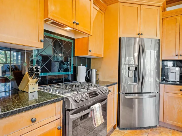 Kitchen with appliances with stainless steel finishes, decorative backsplash, and dark stone countertops