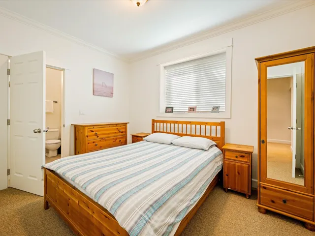 Bedroom with light carpet, ornamental molding, and ensuite bath