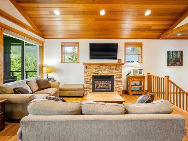 Living room with lofted ceiling, healthy amount of natural light, wood finished floors, wood ceiling, and a fireplace