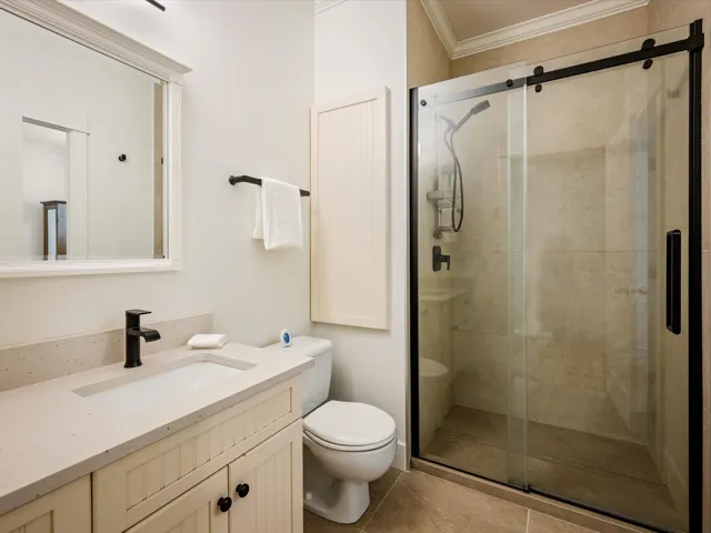 Bathroom featuring crown molding, toilet, vanity, a stall shower, and tile patterned flooring