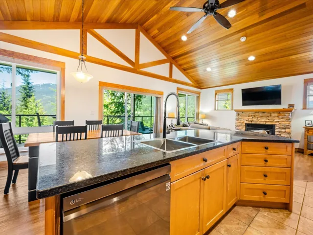 Kitchen with stainless steel dishwasher, wood ceiling, open floor plan, a sink, and vaulted ceiling