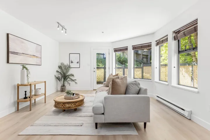 Living area with a baseboard heating unit, light wood finished floors, and rail lighting