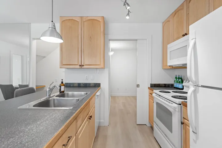 Kitchen featuring light brown cabinetry and white appliances