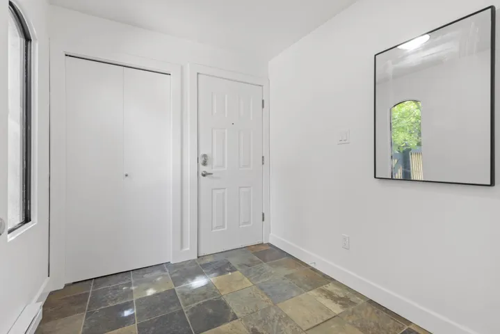 Entrance foyer featuring dark stone finish floors and a baseboard heating unit