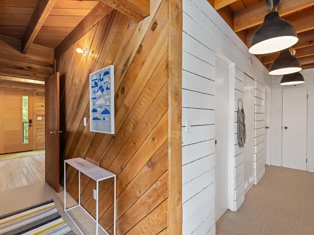 Corridor featuring carpet floors, wood walls, a wooden ceiling with exposed beams, and a sauna