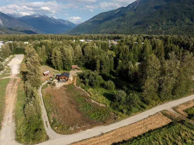 Aerial view of property's location with a mountainous background and a heavily wooded area