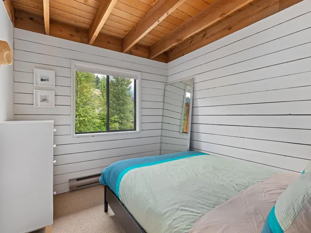 Bedroom with carpet floors, wooden walls, a baseboard radiator, and a wood ceiling with exposed beams
