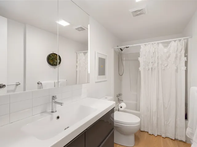 Bathroom with shower / bath combo, light wood finished floors, vanity, and decorative backsplash