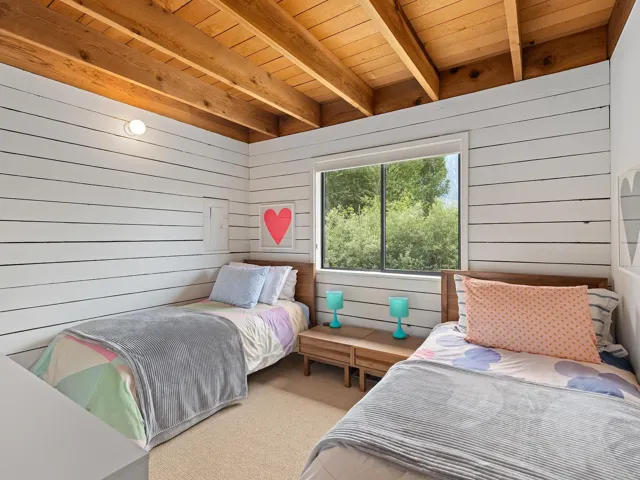 Bedroom with wooden walls, carpet flooring, and a wooden ceiling with exposed beams