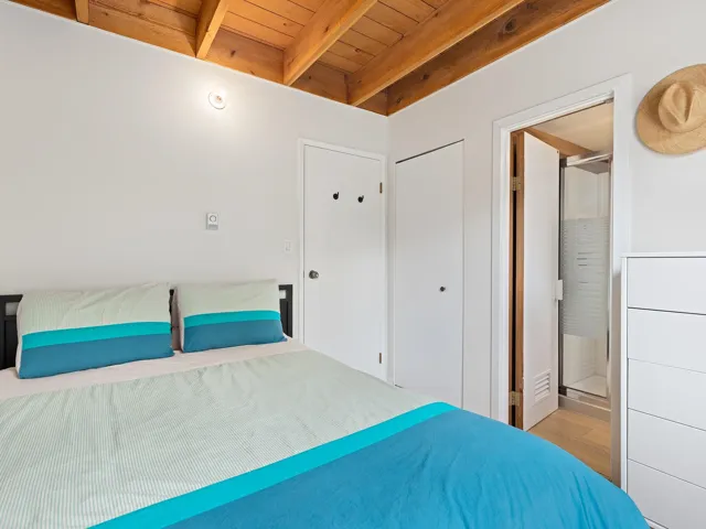 Bedroom with a wooden ceiling with exposed beams, ensuite bathroom, and wood finished floors