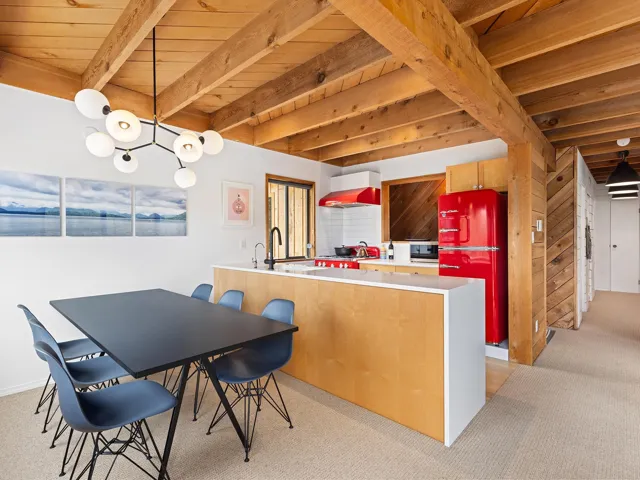 Dining room featuring light carpet and a wooden ceiling with exposed beams