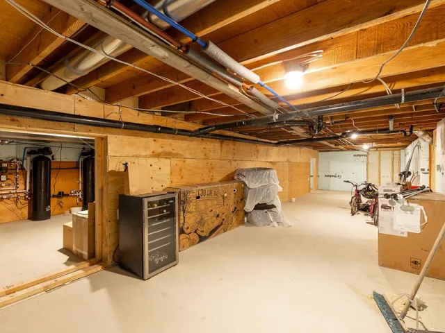 Unfinished below grade area with wine cooler and a water softener system