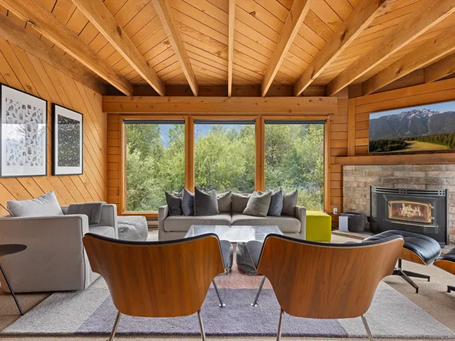 Living room with wood walls, a fireplace, plenty of natural light, and a wooden ceiling with exposed beams