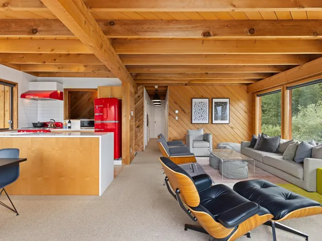 Living room featuring wood walls, light carpet, and a wood ceiling with exposed beams