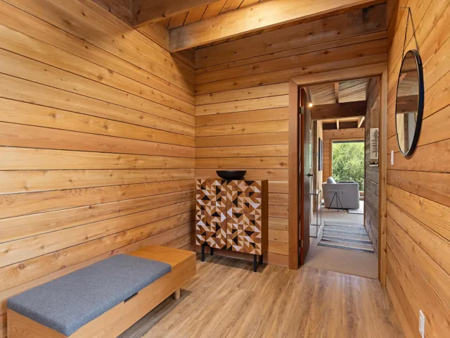 Living area featuring wood finished floors, wooden walls, and beam ceiling