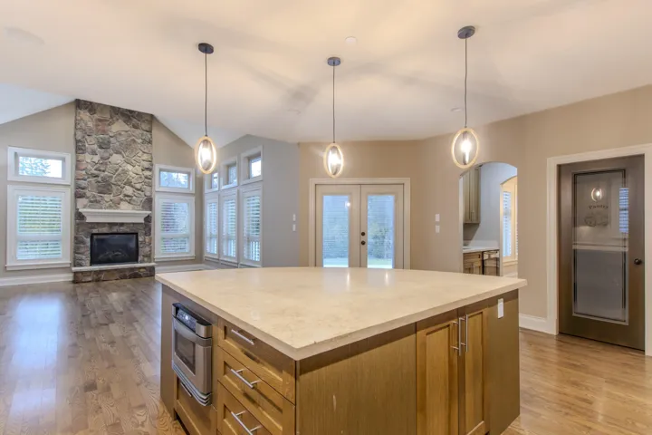 Kitchen with light wood-style floors, a kitchen island, hanging light fixtures, open floor plan, and lofted ceiling