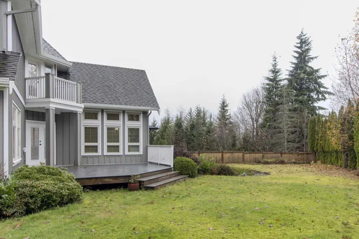 View of yard with a wooden deck and a balcony