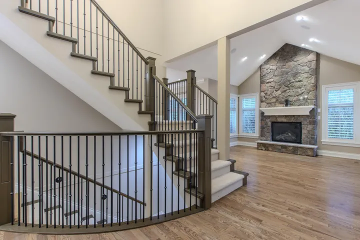 Staircase featuring a high ceiling, wood finished floors, and a stone fireplace