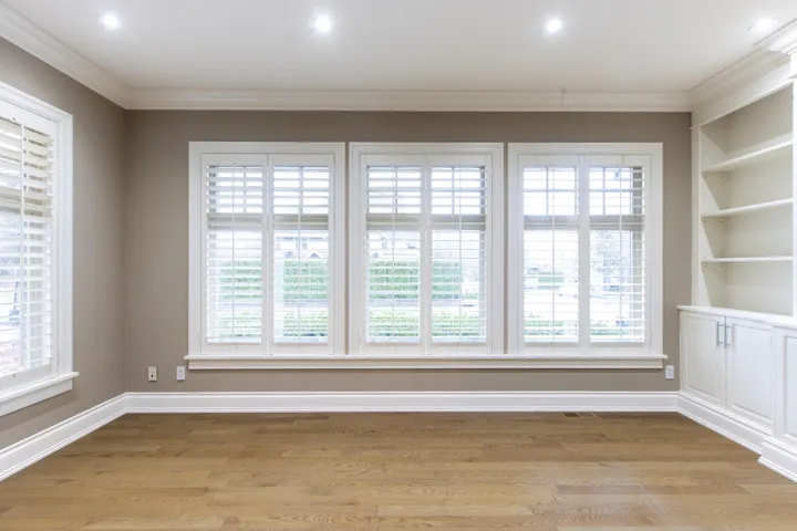 Empty room featuring light wood-style floors, ornamental molding, and built in shelves