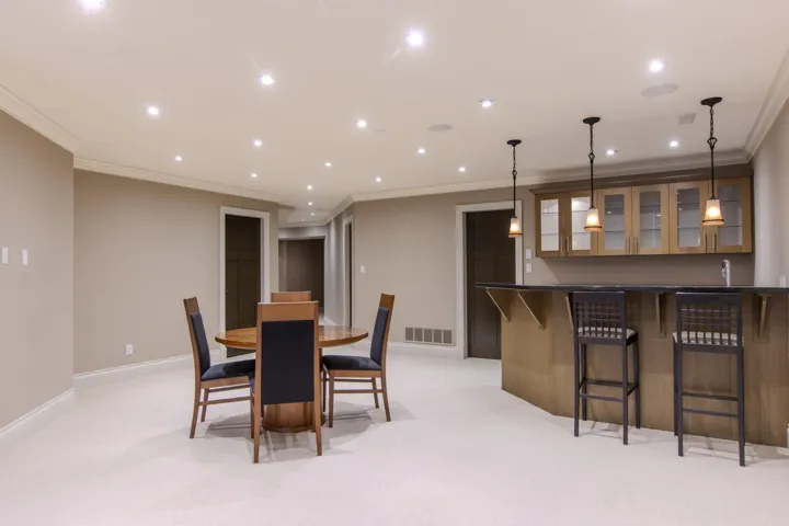 Dining area with recessed lighting, ornamental molding, light colored carpet, and bar area