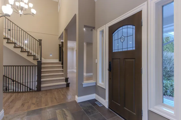 Foyer entrance featuring stairs, healthy amount of natural light, a chandelier, and stone tile floors