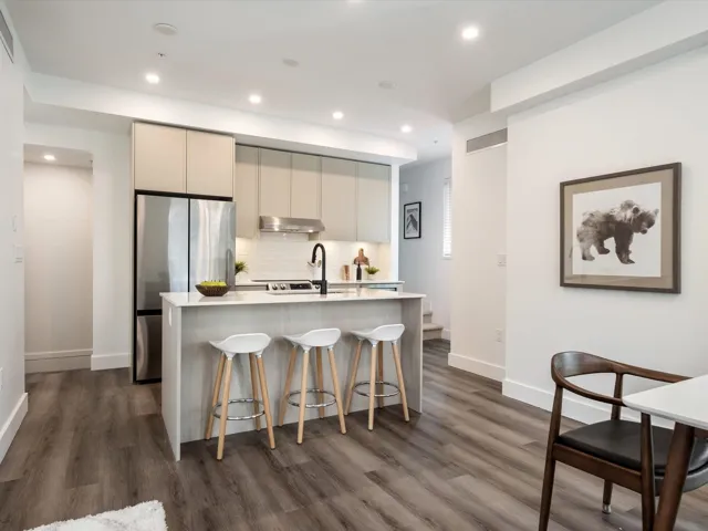 Kitchen featuring a breakfast bar, an island with sink, light countertops, modern cabinets, and backsplash