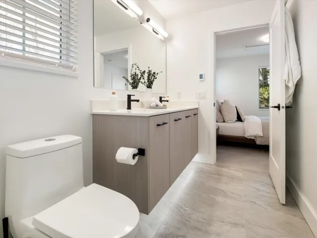 Full bath with toilet, a sink, ensuite bath, double vanity, and baseboards