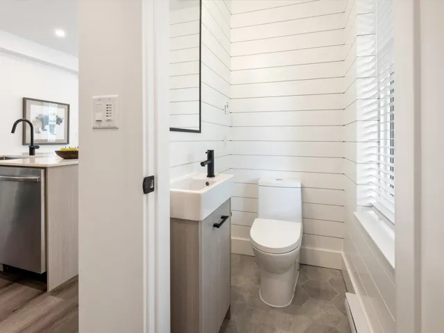 Bathroom with wooden walls, toilet, and vanity