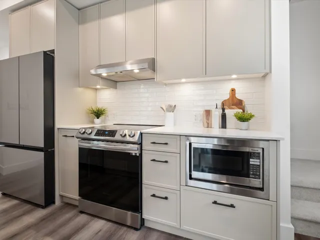 Kitchen with light countertops, backsplash, under cabinet range hood, and stainless steel appliances
