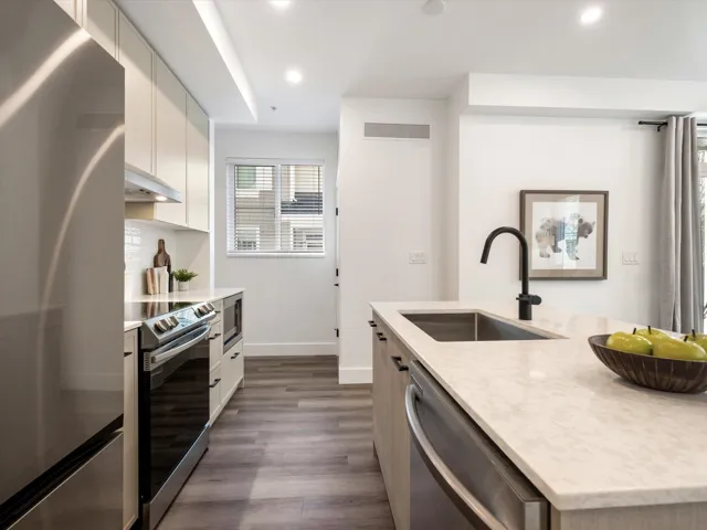 Kitchen featuring visible vents, a sink, under cabinet range hood, dark wood finished floors, and stainless steel appliances