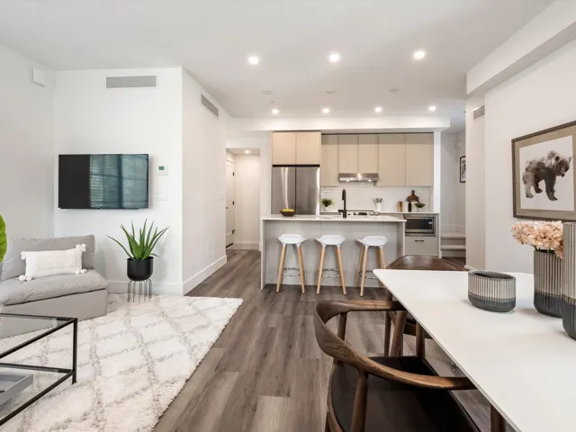 Kitchen with a kitchen bar, visible vents, an island with sink, under cabinet range hood, and stainless steel appliances