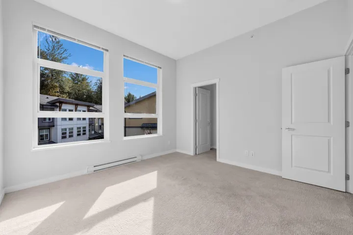 Open-concept living area featuring wood-finish flooring, recessed lighting, and a kitchen with white cabinetry and stainless steel appliances