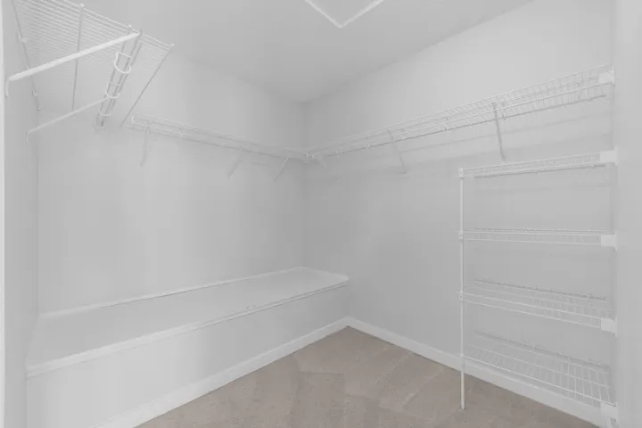 Spacious open-concept living area featuring pristine white walls, recessed lighting, and warm wood-finish flooring throughout