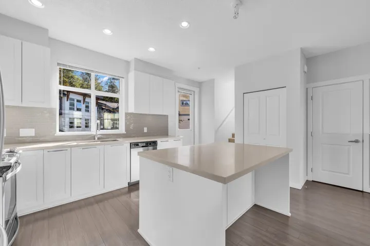 Contemporary multi-level townhome featuring a modern roofline and a second-story balcony with metal railings