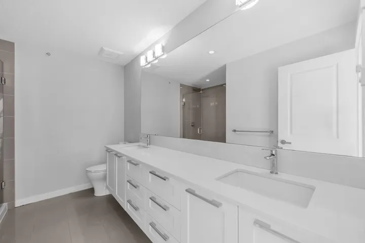 Kitchen featuring an island, integrated stainless steel appliances, light-toned countertops, white cabinetry, and wood-finish flooring