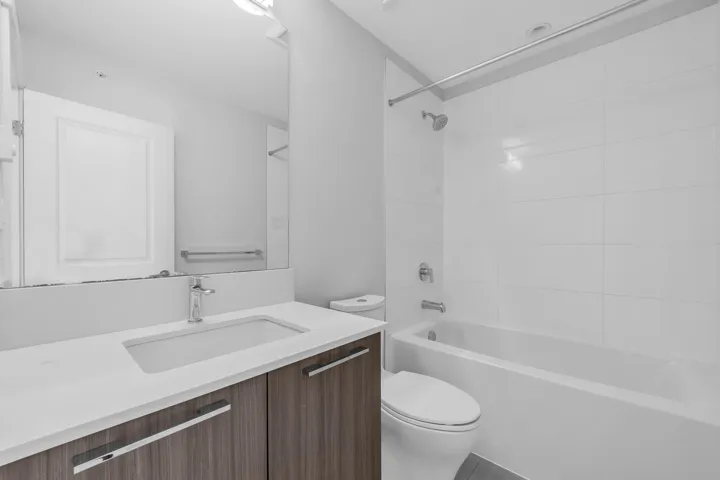 White shaker cabinetry, stainless steel appliances, wood-finish flooring, recessed lighting, and a kitchen island with built-in microwave