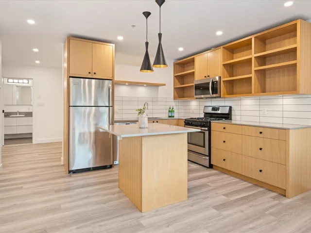 Kitchen featuring light brown cabinetry, stainless steel appliances, a center island, backsplash, and recessed lighting